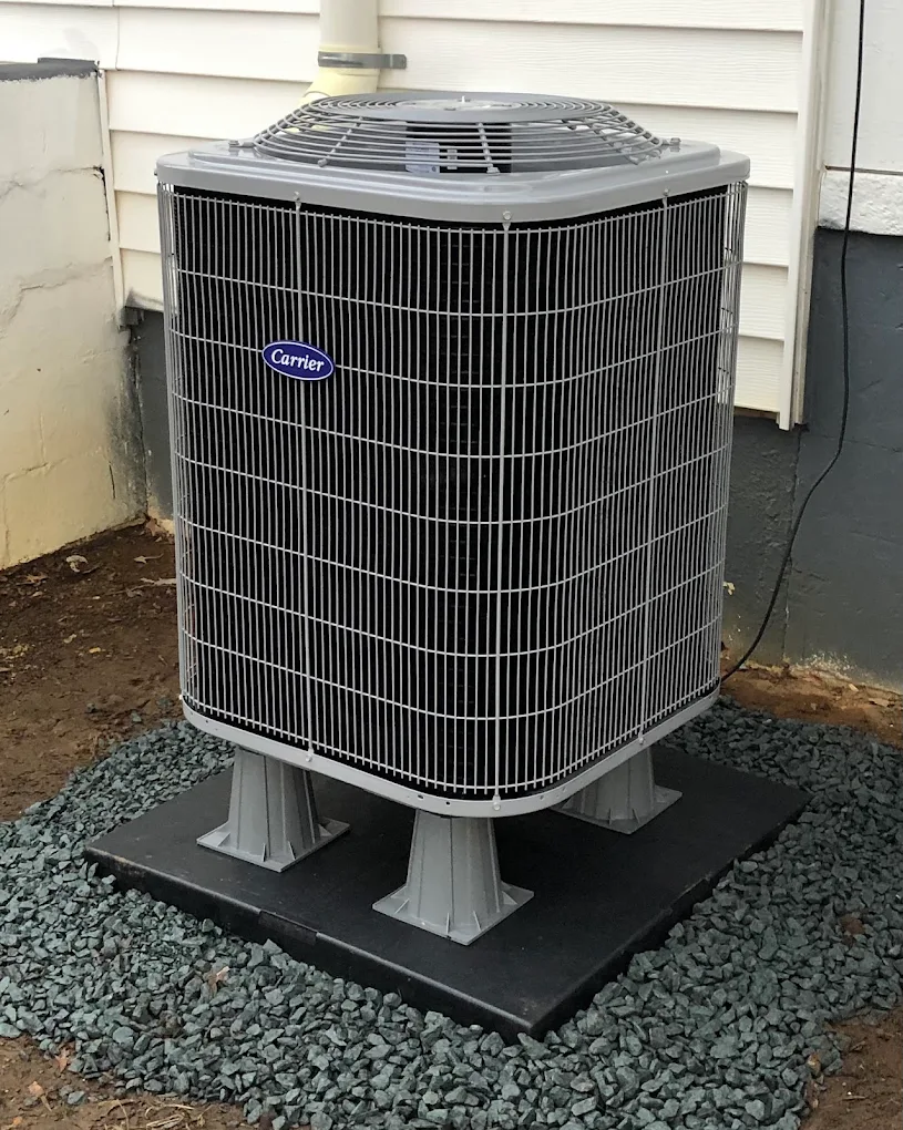 Carrier AC condenser installation on a leveled composite pad — Annapolis, MD. New Carrier air conditioner condenser installed on a composite pad at an Annapolis, MD home