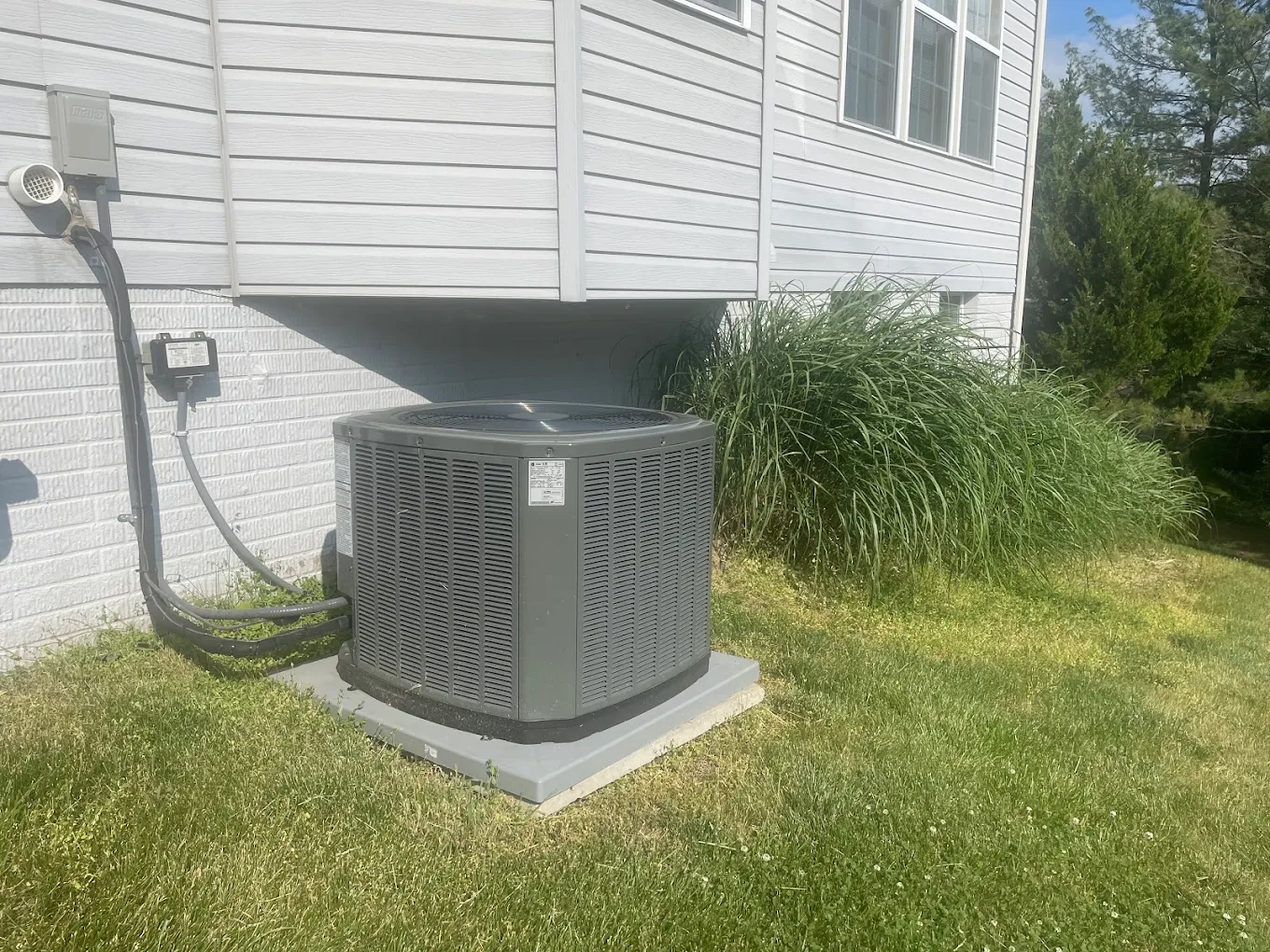 Replacement residential AC condenser set on a concrete pad beside an Arnold, Maryland home